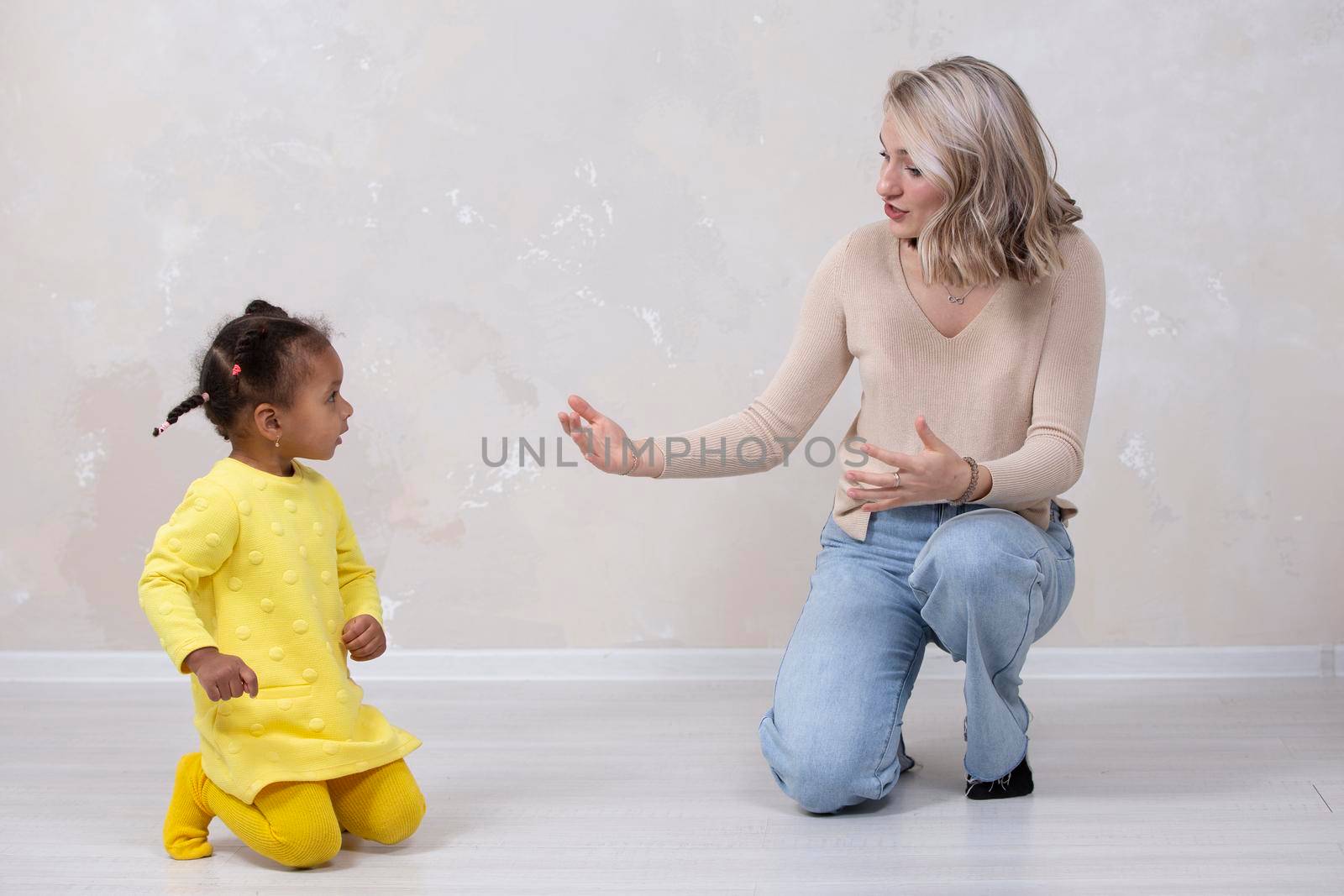 Multiethnic mom and daughter play at home. Cheerful mother with little daughter of African nationality. Family from different races.
