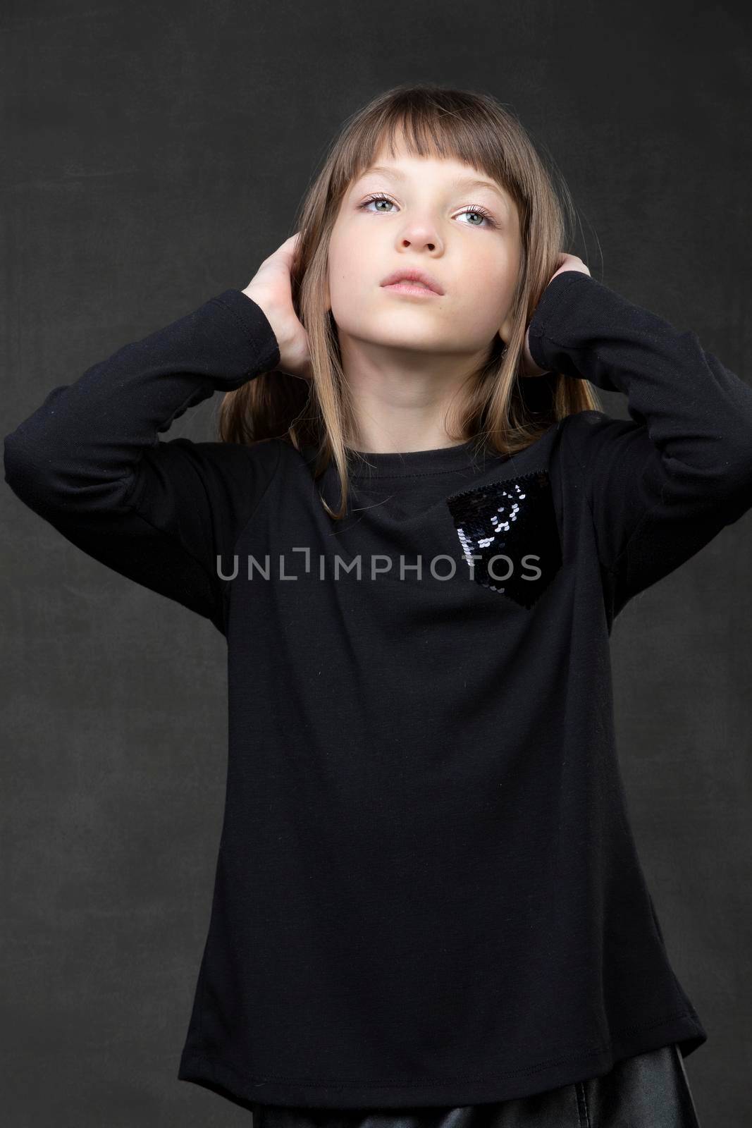 Portrait of a beautiful pensive teenage girl on a gray background.