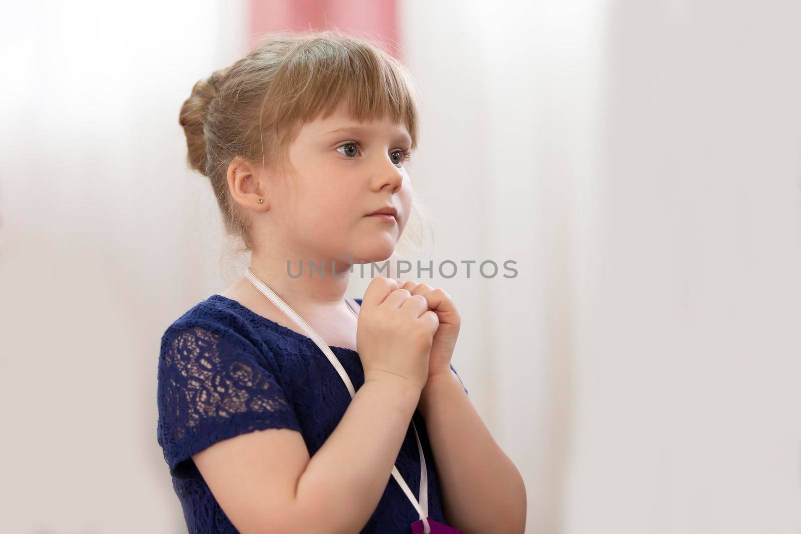 A five-year-old girl stands in profile with her arms folded.