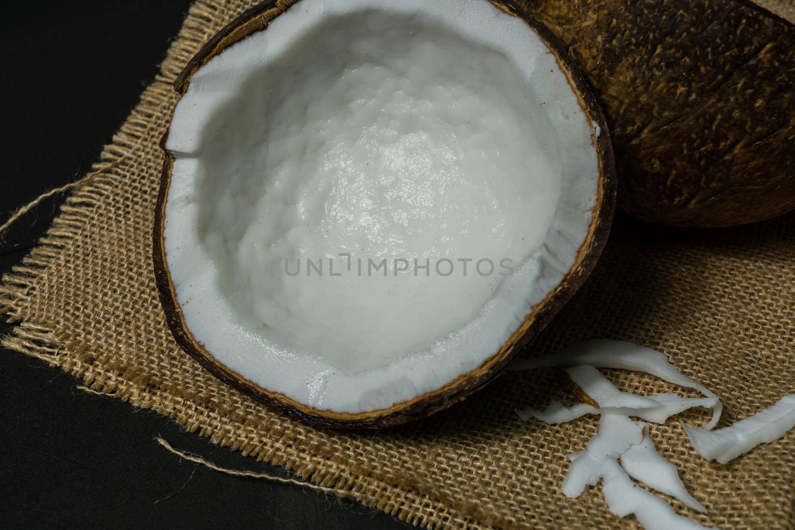 fresh coconut on black background drawing its water, raffia cloth