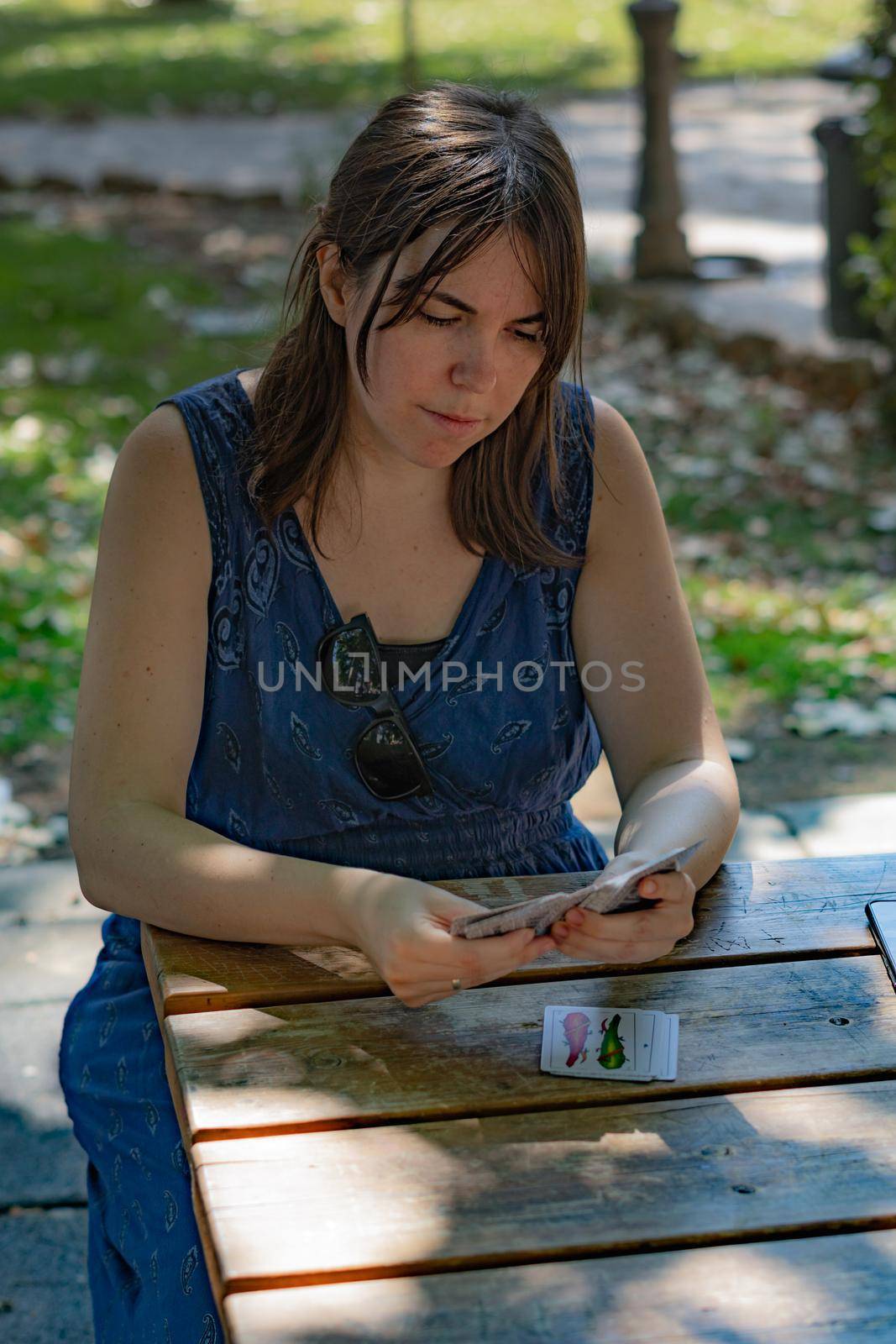 woman playing cards in the park by joseantona