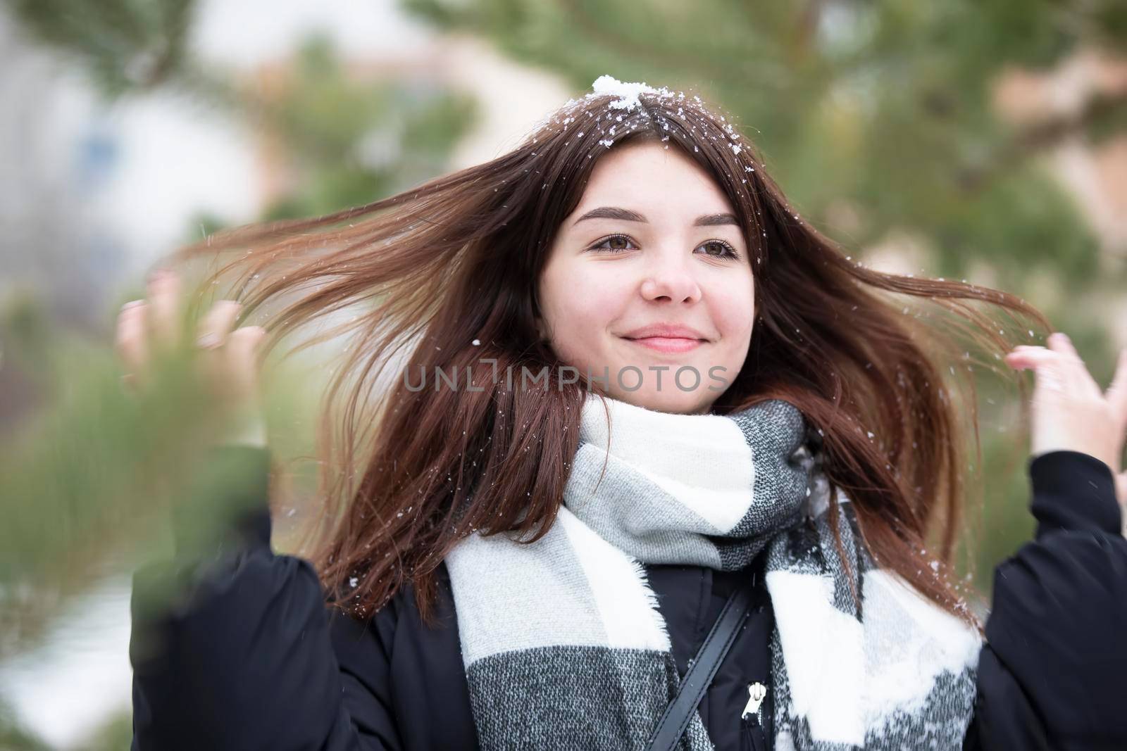 Happy teen girl with long snowy hair in winter.