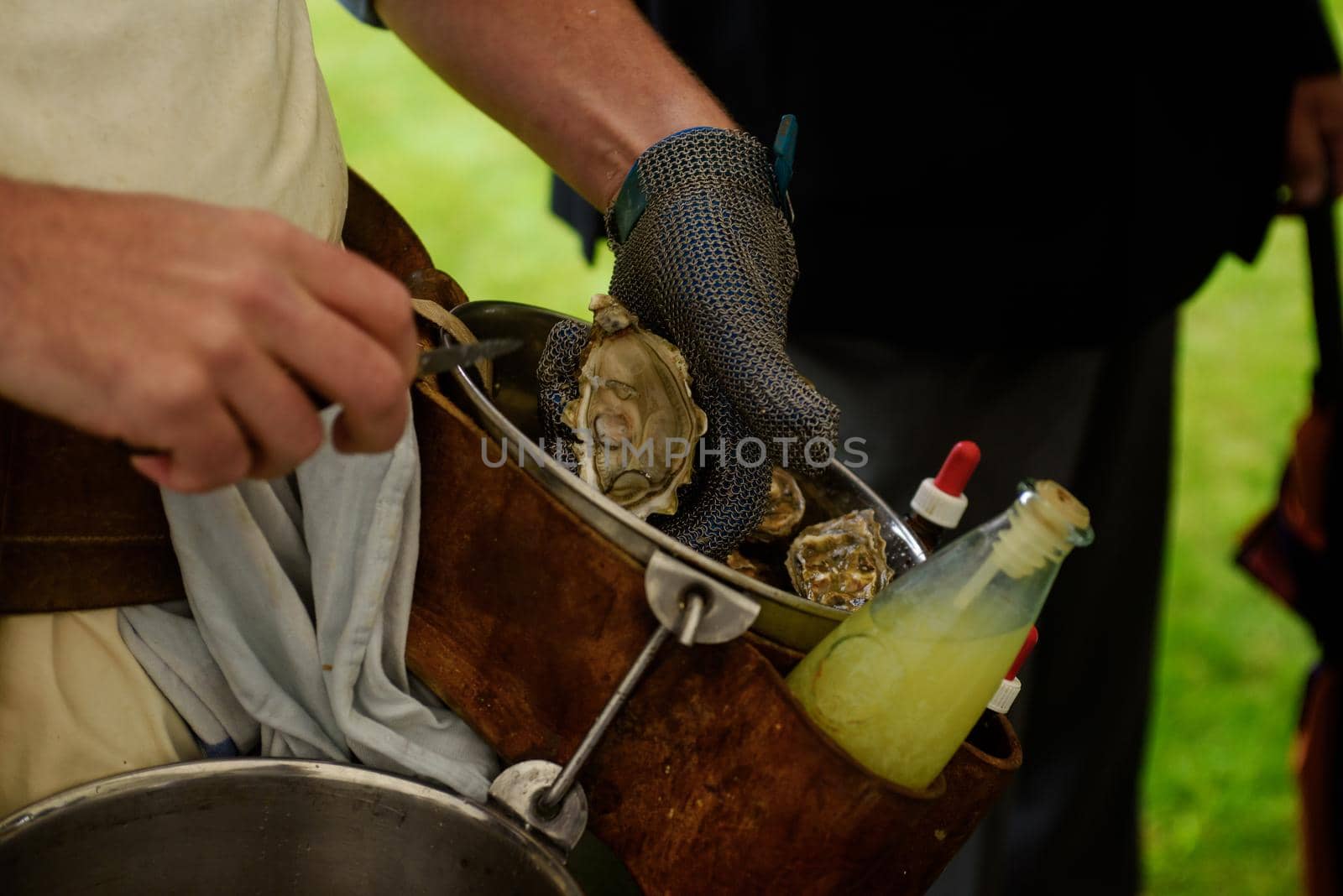 closeup of the hand of a man with a chainmail glove chucking an oyster