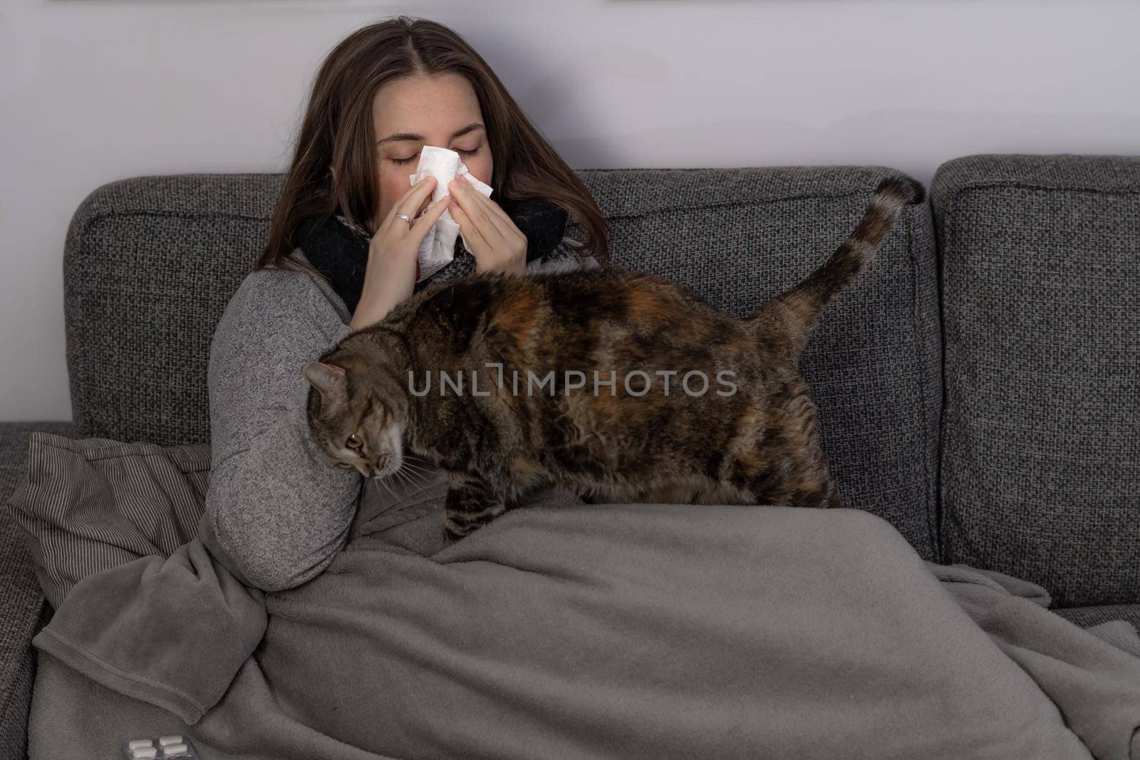 chica joven enferma tumbada en el sofa con su gato by joseantona