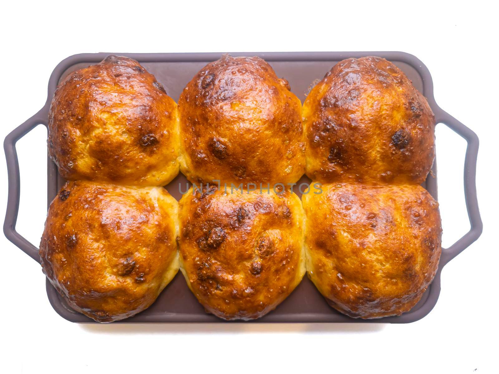 Lush buns with a golden crust in a silicone mold on top.