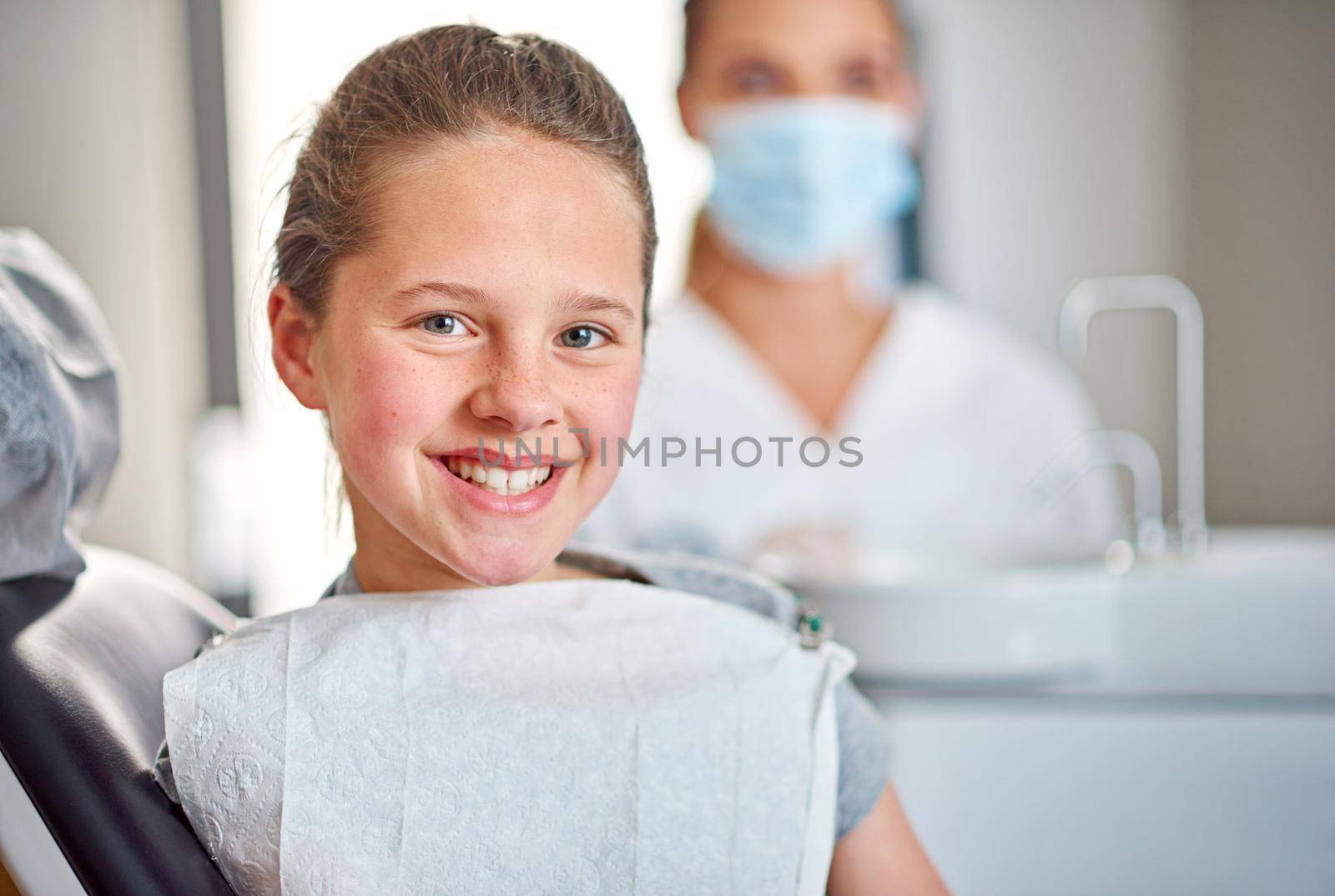 Shes got nothing to worry about. A young girl sitting in a dental chair with her dentist in the background