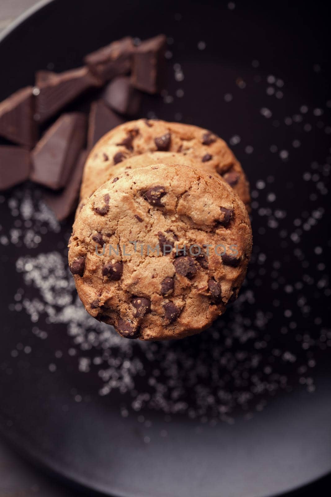 Chocolate chip cookies on black plate. Dark old wooden table.