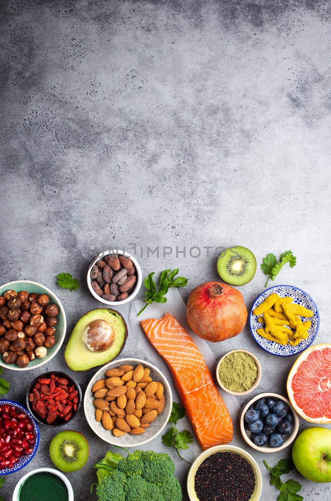 Selection of healthy products and superfoods: salmon, fruit, vegetables, berries, goji, spirulina, matcha, quinoa, chia, nuts with copy space. Clean eating concept, gray background, top view, close up