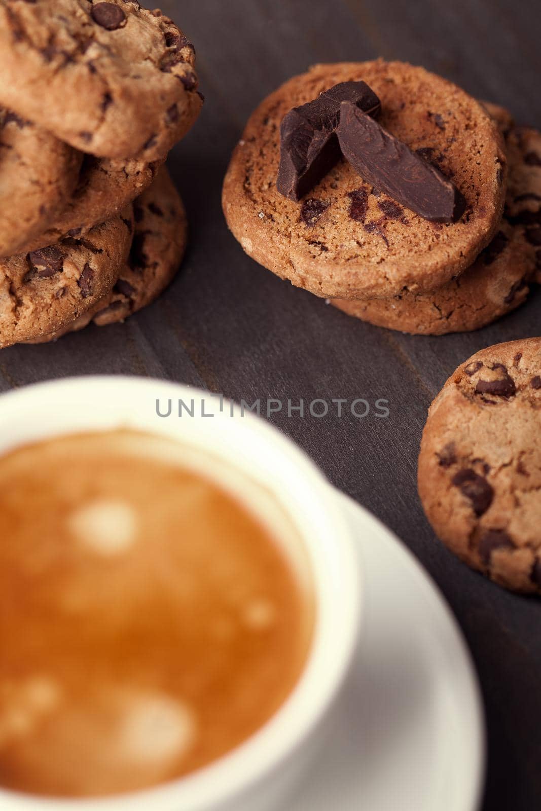 Homemade chocolate chip cookies and a cup of coffee on dark old wooden table. Sweet dessert.