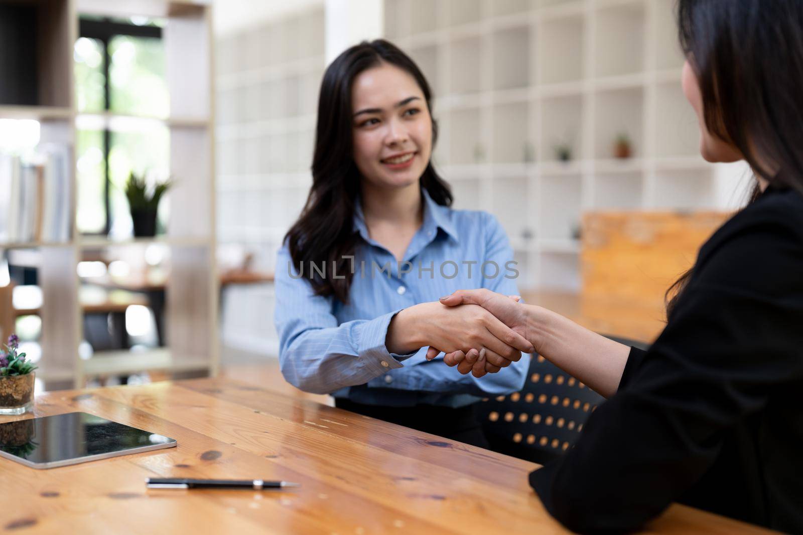 Portrait young asian woman interviewer and adviser shaking hands for a job interview. Business people handshake in modern office. Greeting deal concept.