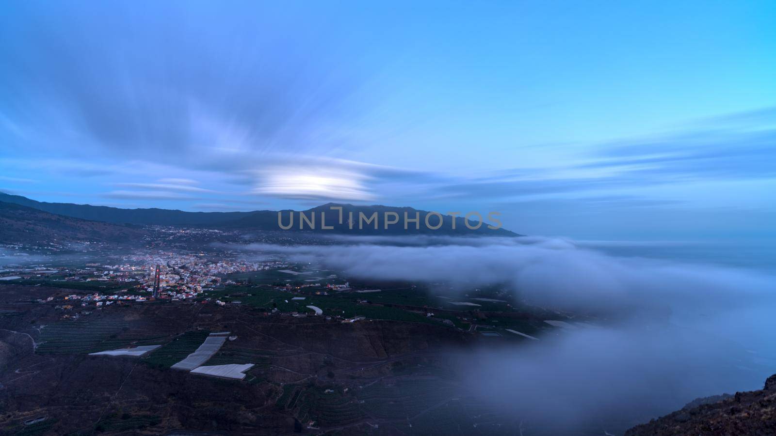 Smoking cumbre vieja volcano with El Paso and Los llanos cities at dusk, long exposure wide angle