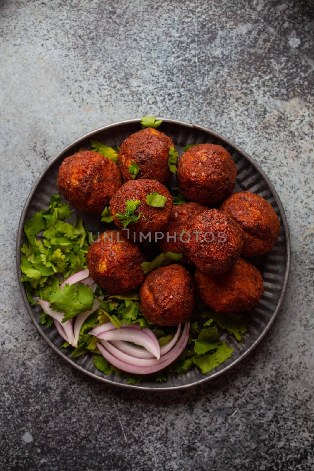 Traditional Middle eastern dish falafel served with fresh green cilantro and onion salad. Arab or Mediterranean appetizer falafel served on rustic background table. Top view.