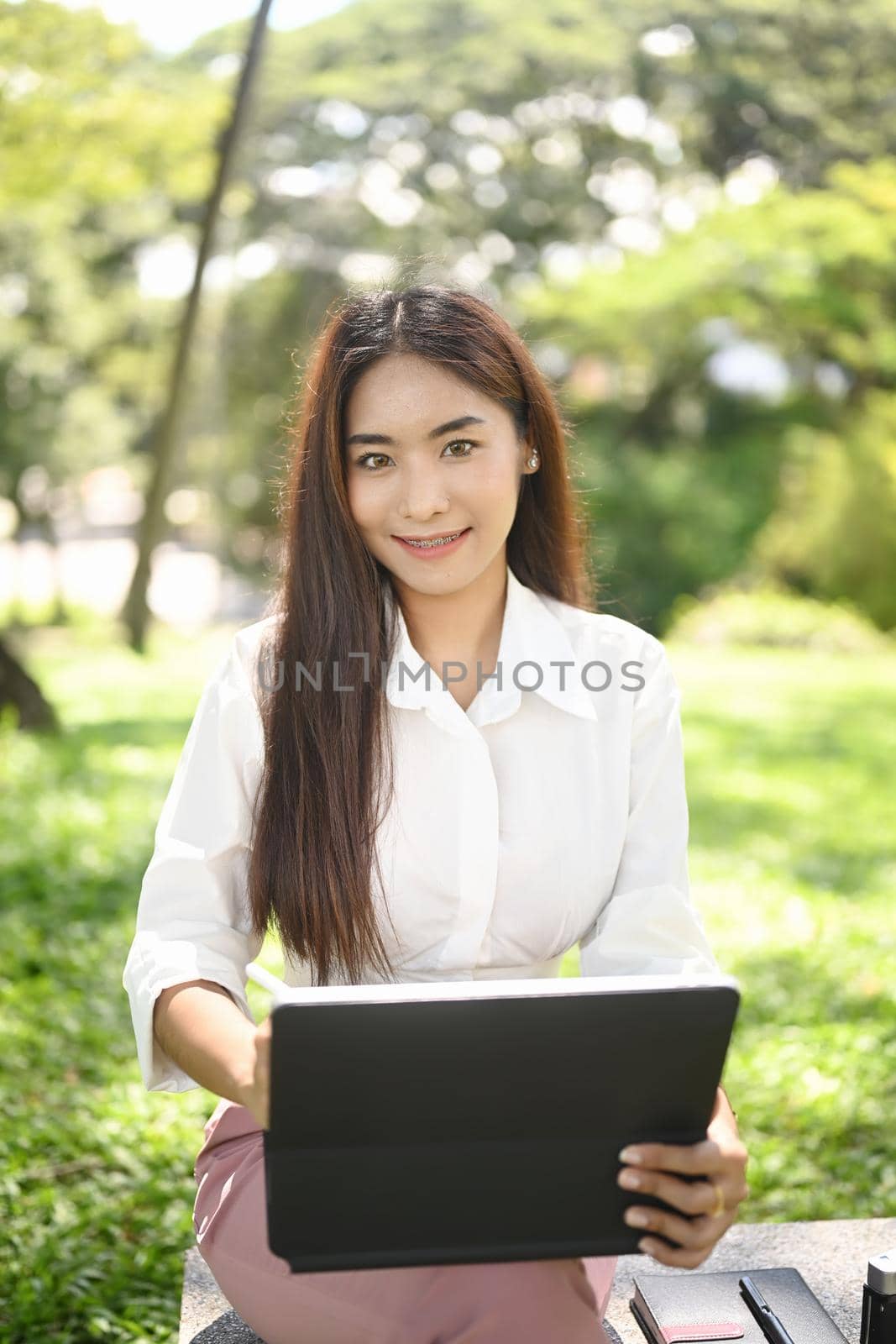 Portrait of attractive woman worker working with computer tablet in the park.