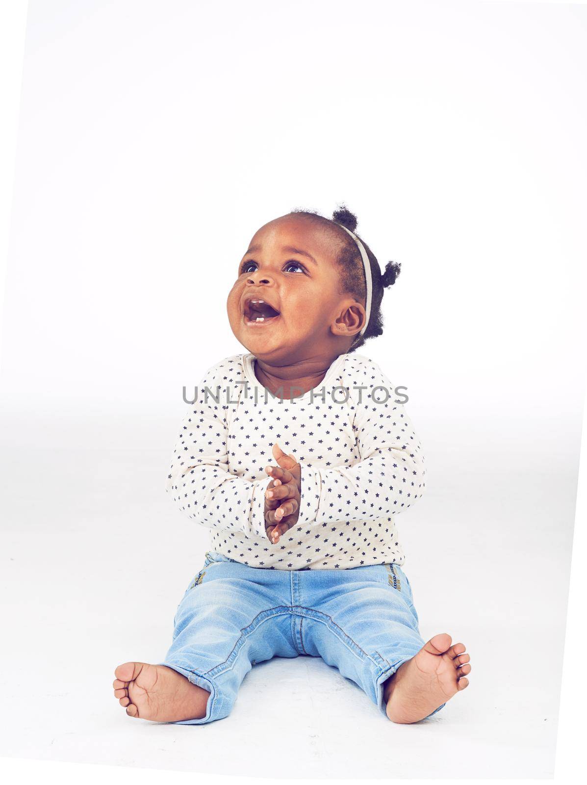 I like it. Studio shot of a happy baby girl sitting against a white background