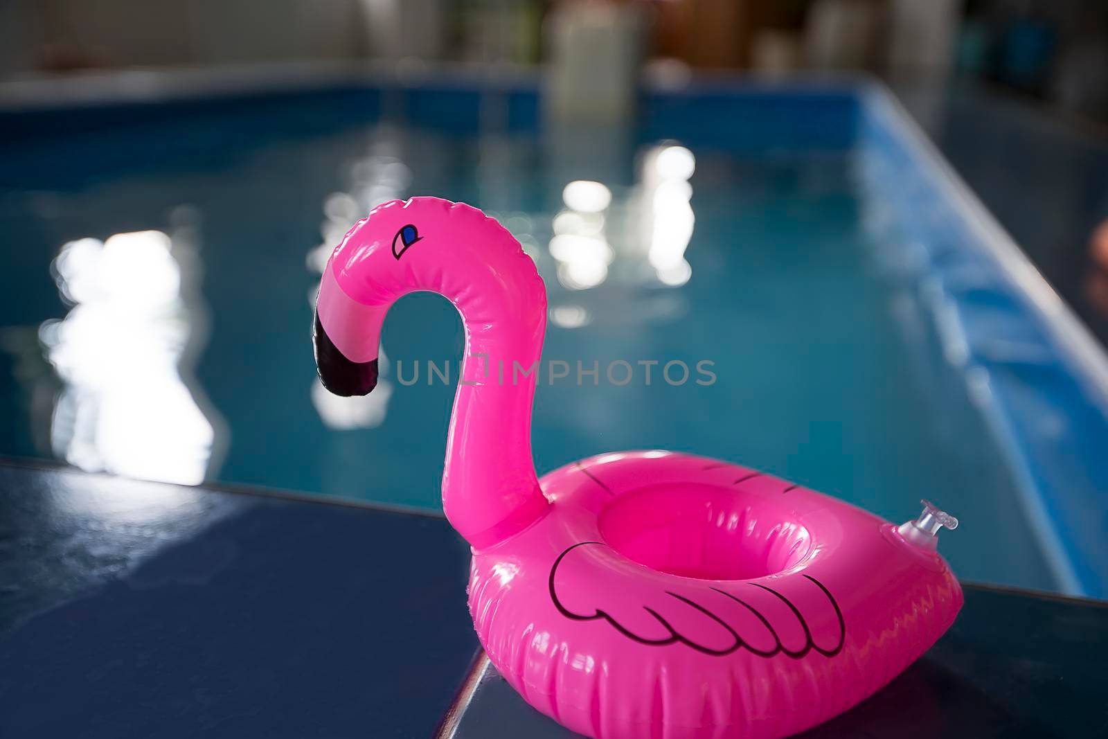Toy pink flamingo on the background of the pool