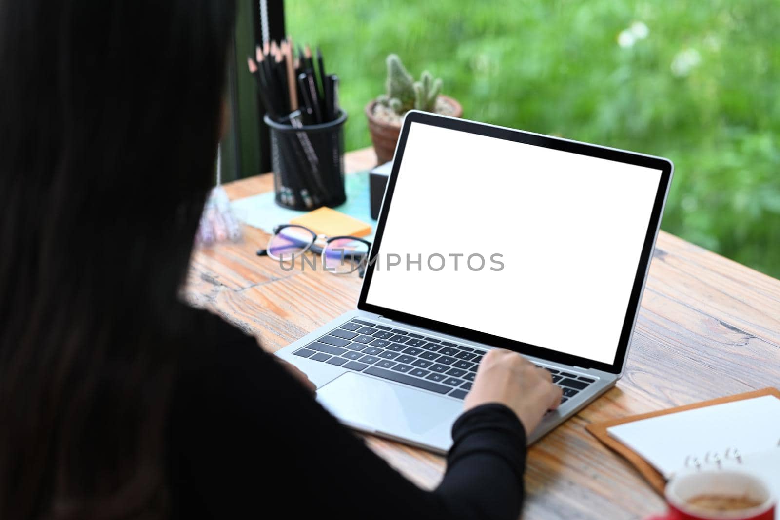 Over shoulder view of creative woman working with laptop computer. by prathanchorruangsak