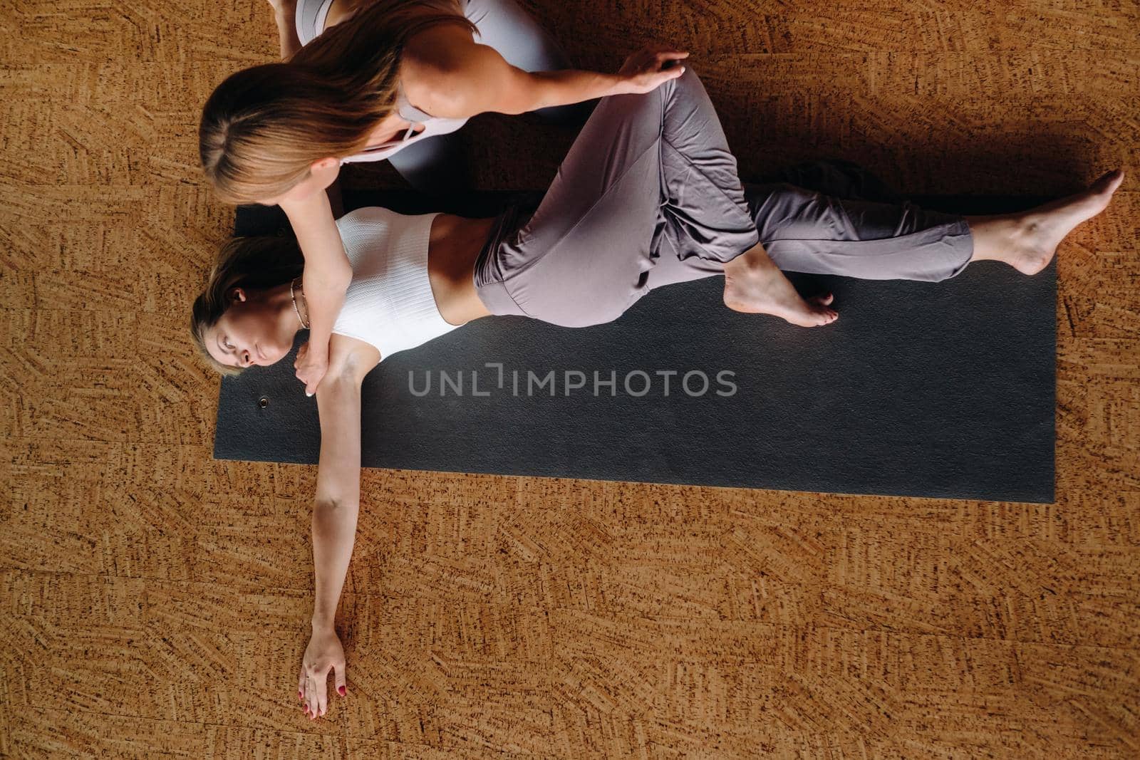 Yoga exercises. A personal trainer teaches a woman yoga classes in the gym by Lobachad