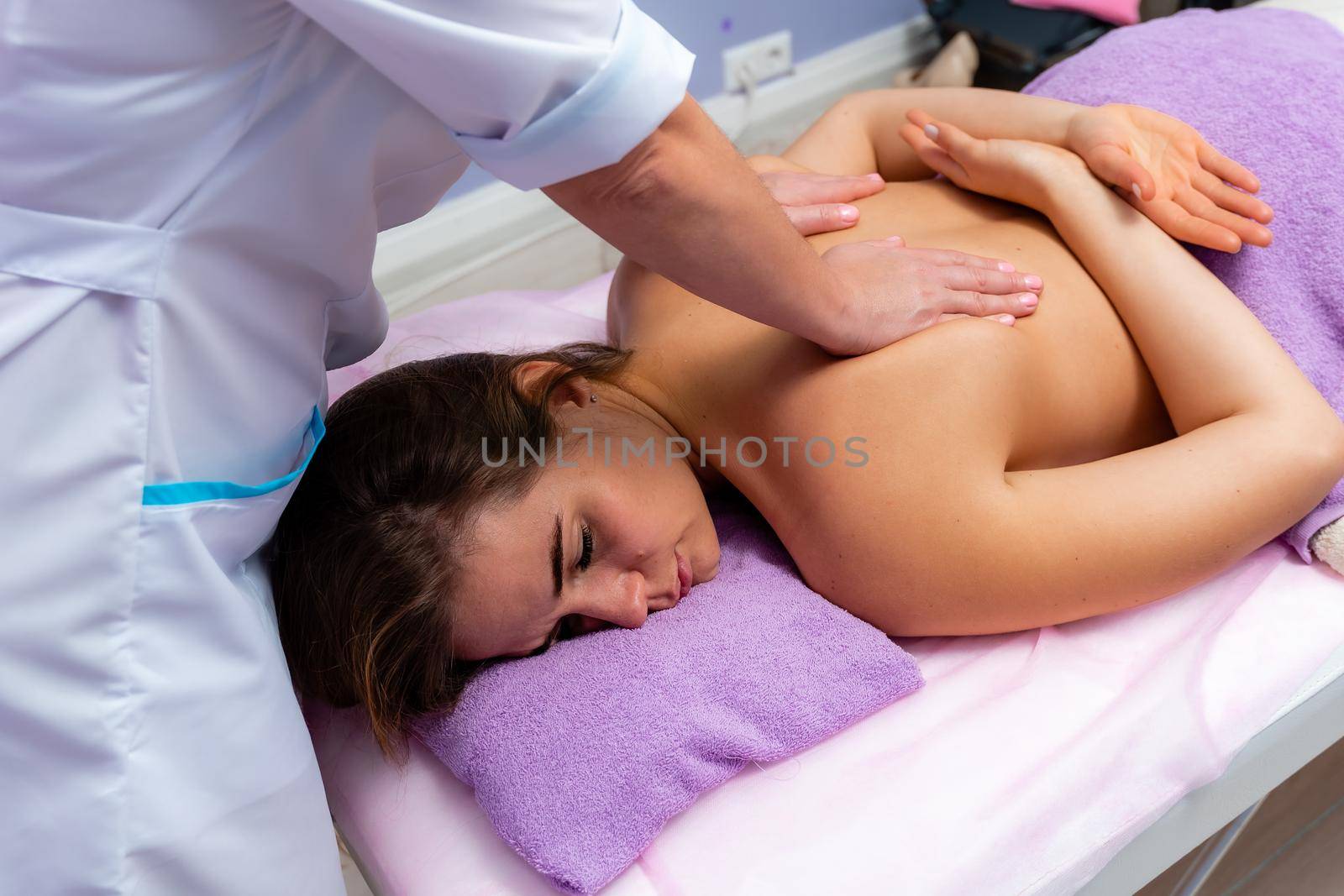 Blonde massage therapist massaging a woman. Woman getting a massage at the spa.