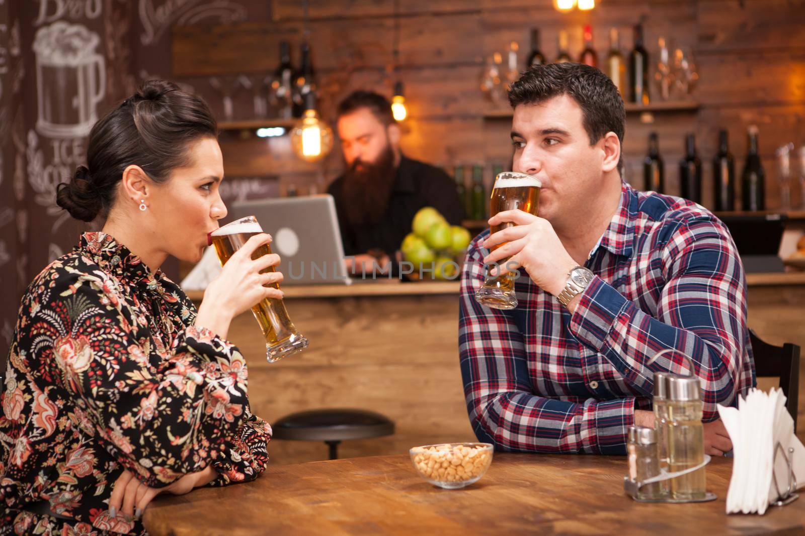 Romantic Couple drinking beer in in a hipster pub and making a toast. by DCStudio