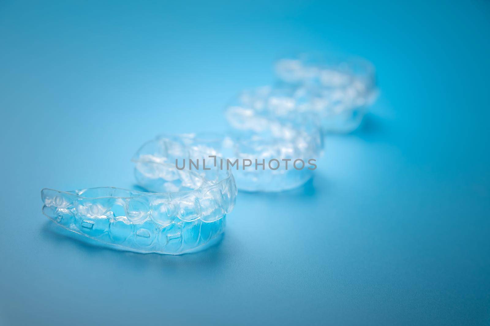 Invisible aligners on a blue background with copy space. Plastic braces for teeth alignment.
