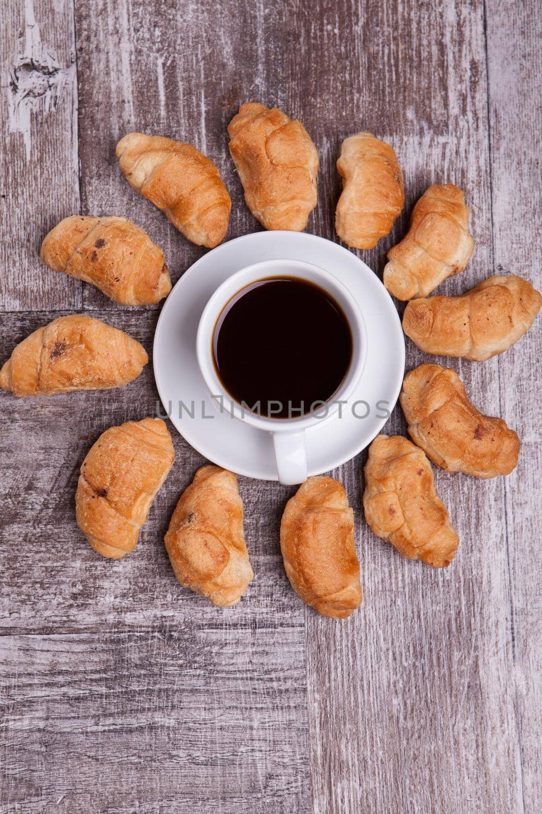 Freshly baked croissants on rustic wooden table with cup of coffee. Delicious coffee.