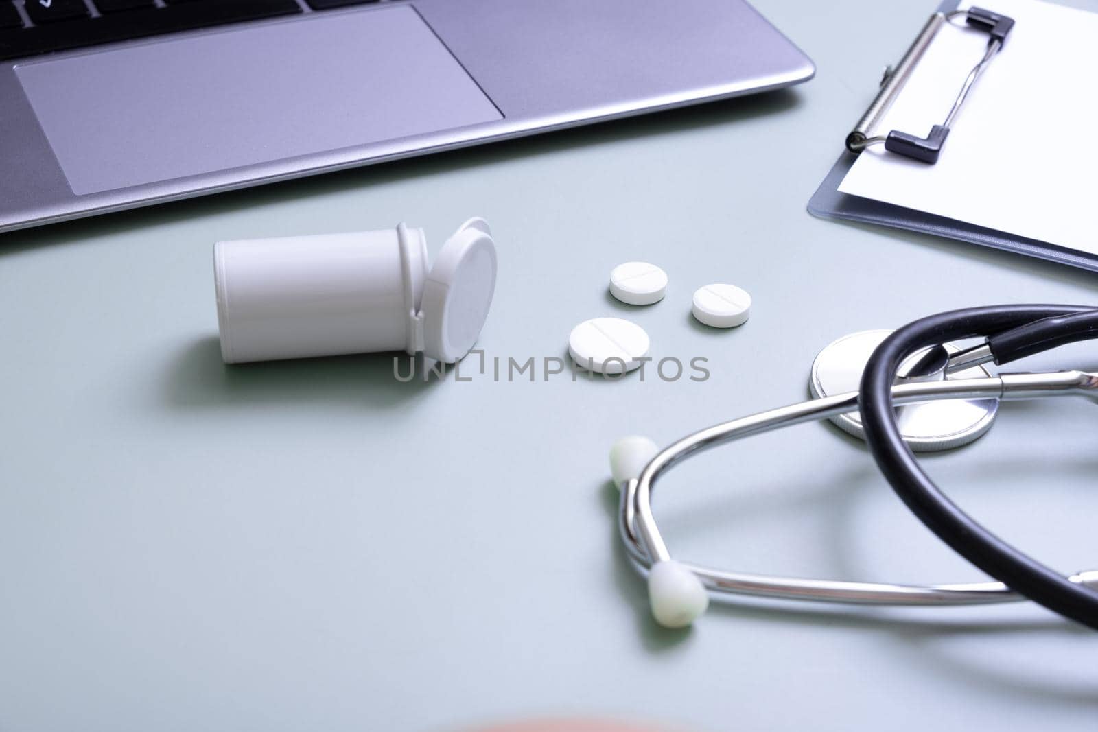 Pills, stethoscope with laptop and tablet at doctor's workplace. Variative focus.
