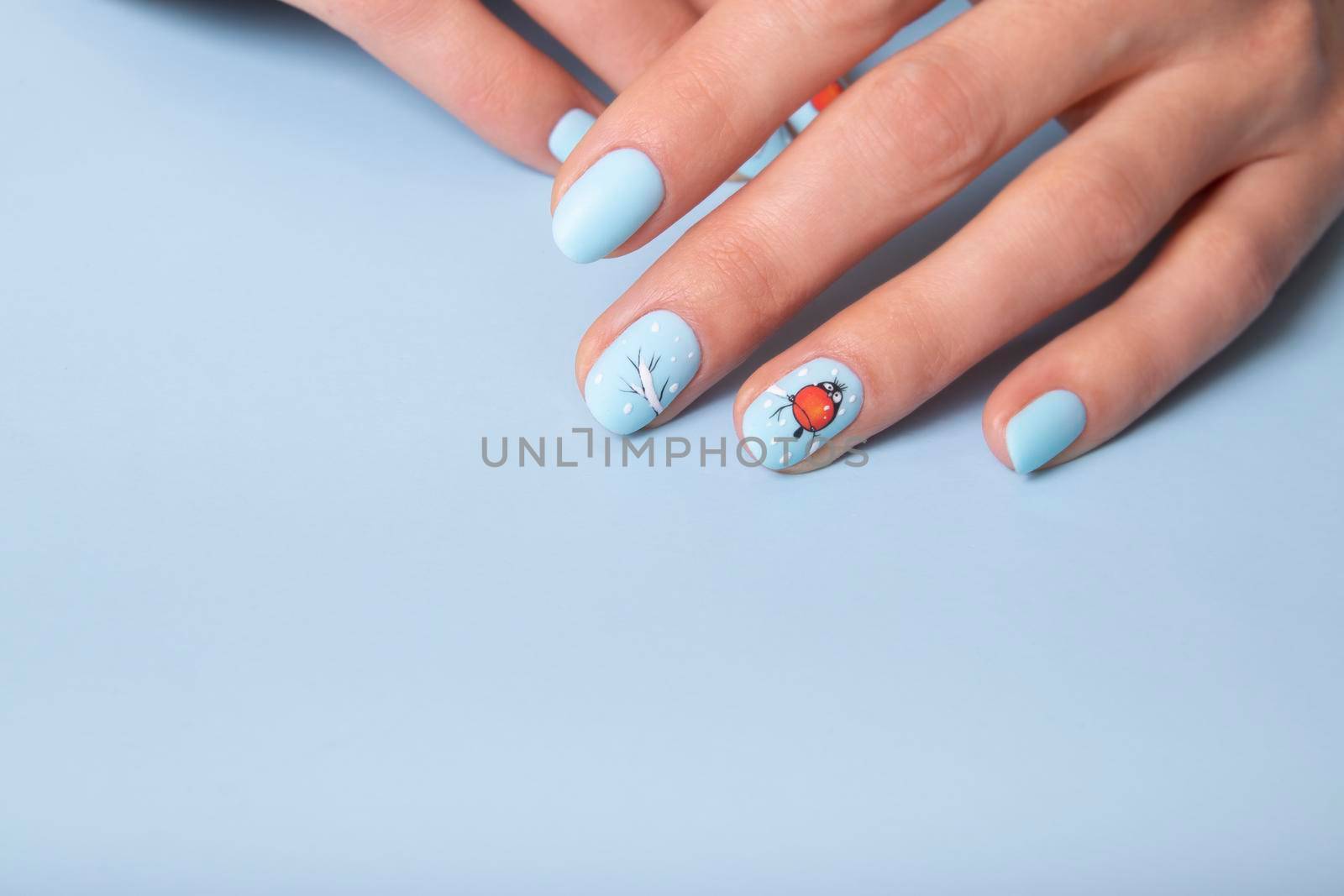 Female hands with winter snow manicure with stickers under a matte top.