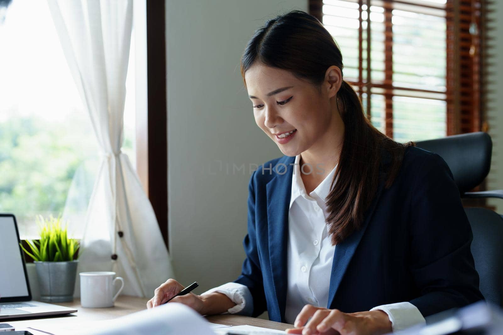 Portrait of an Asian accountant checking accounts for customers.