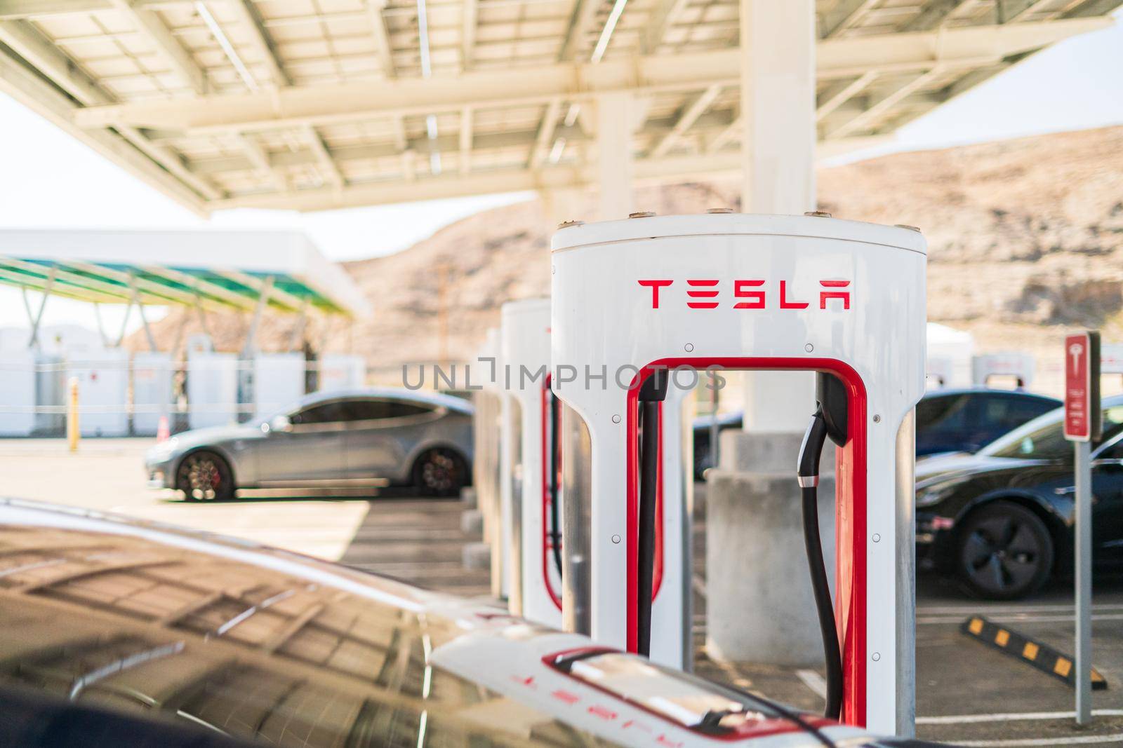 Baker, California, USA-October 12, 2021 - Tesla supercharging station during the day.