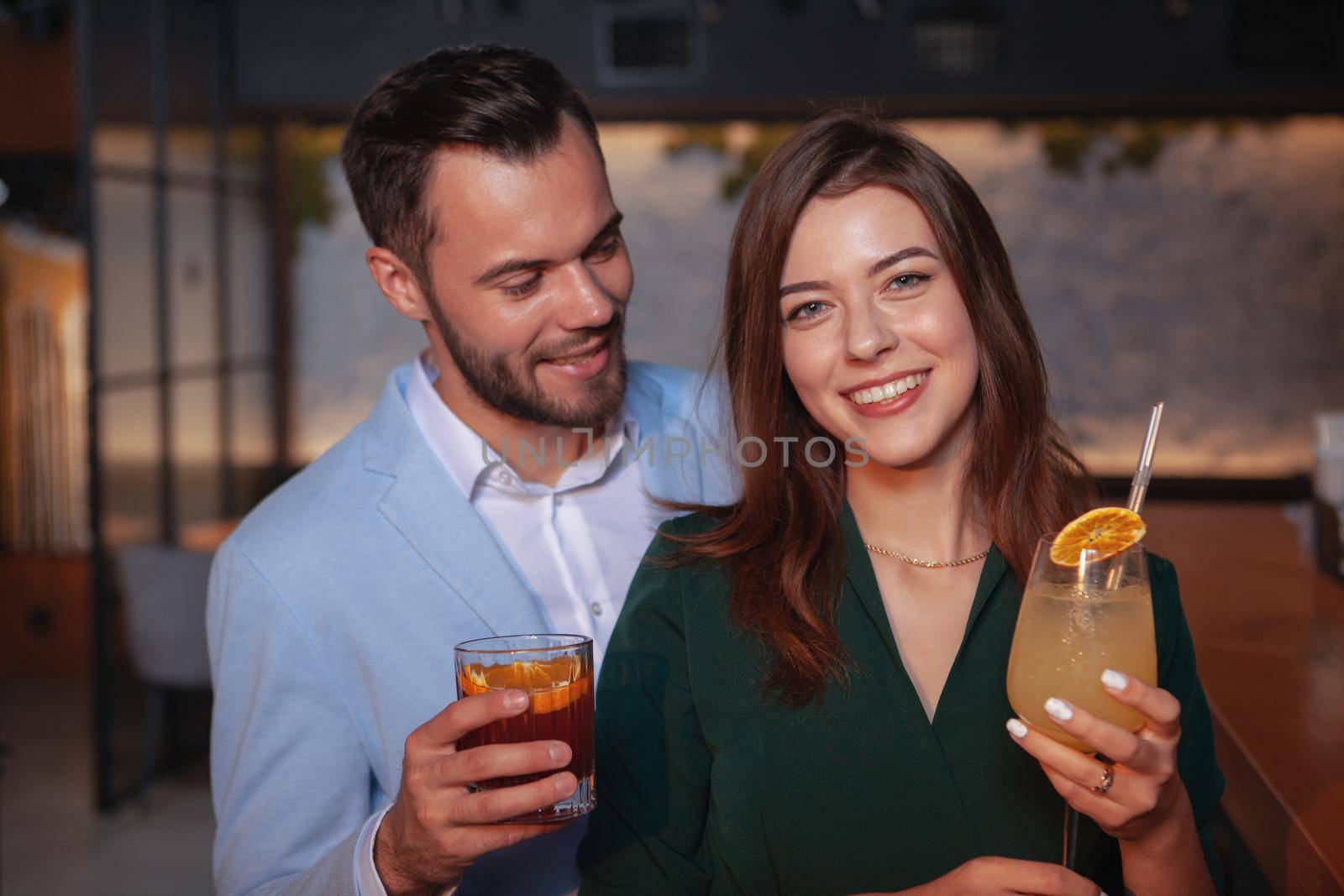 Gorgeous happy woman smiling to the camera, enjoying night out with her man at coctail bar. Celebration, passion, party concept