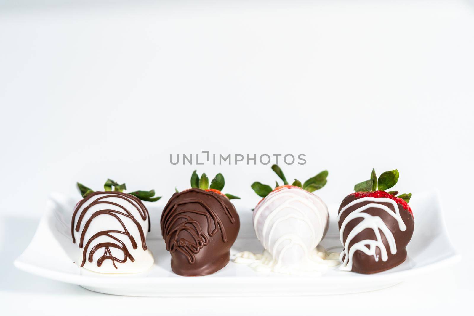 White and dark chocolate dipped strawberries on a white cake stand.