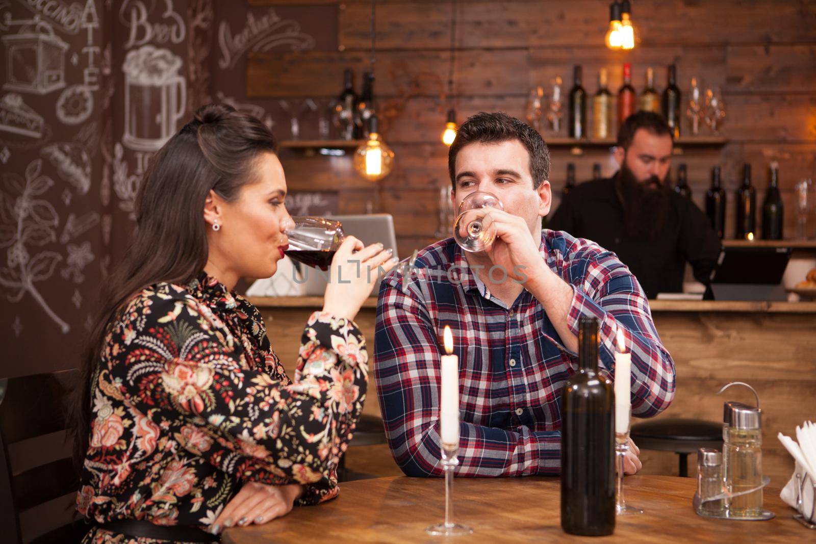 Couple drinking red wine and sharing a beautiful moment in a hipster pub. Joy time.
