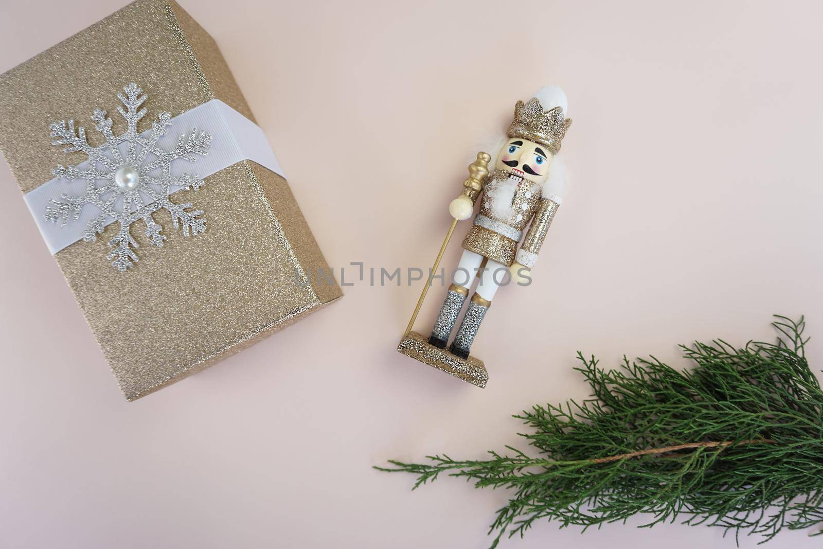 On the table there is a wooden Nutcracker toy, a gift in a gold package and a coniferous branch by Spirina