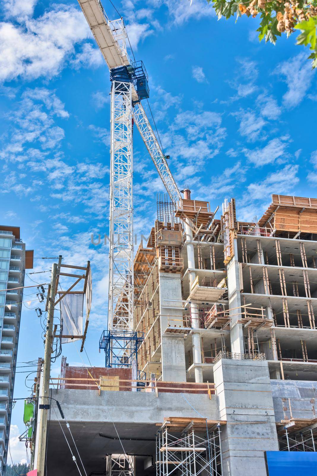 Concrete high rise residential building under constraction on blue sky background