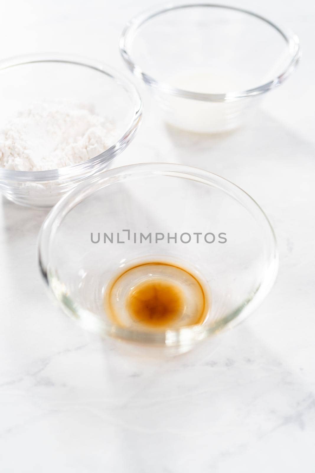 Measured ingredients in glass bowls to prepare a white bread glaze.