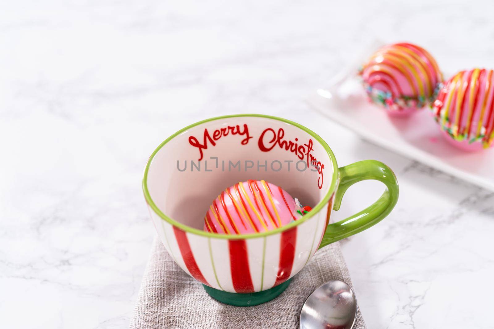 Preparing Christmas hot chocolate bombs with hot milk in a Christmas mug.