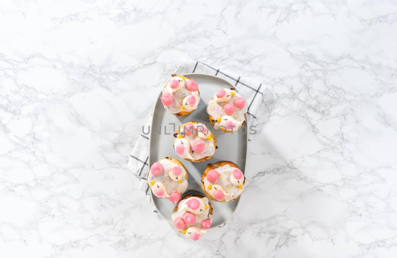 Freshly baked mini Easter bread kulich with lemon glaze, decorated with sprinkles and meringue bird-shaped cookies.