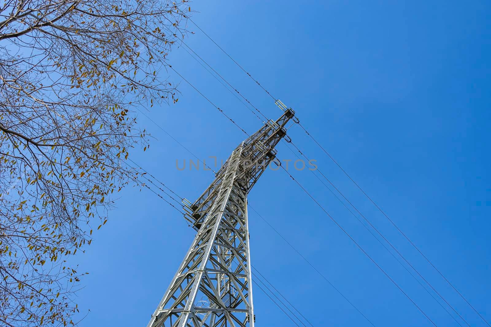 View from below of a power transmission tower against the sky. City infrastructure