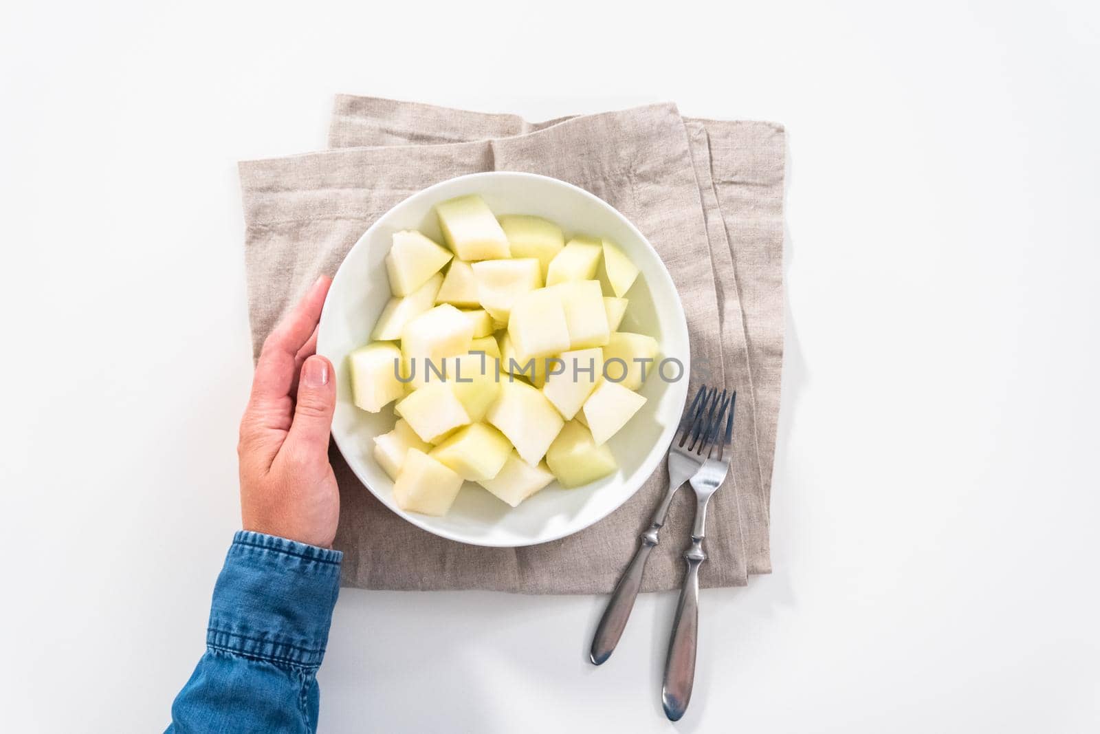 Flat lay. Sliced golden dewlicious melon in a white bowl.