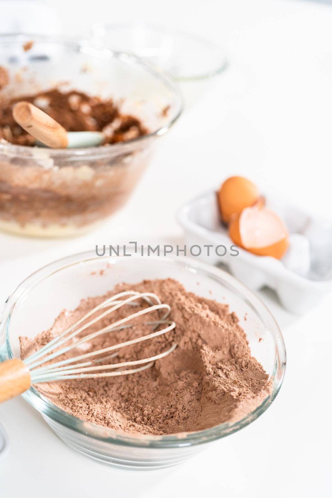 Mixing ingredients in a glass mixing bowl to bake chocolate cookies.