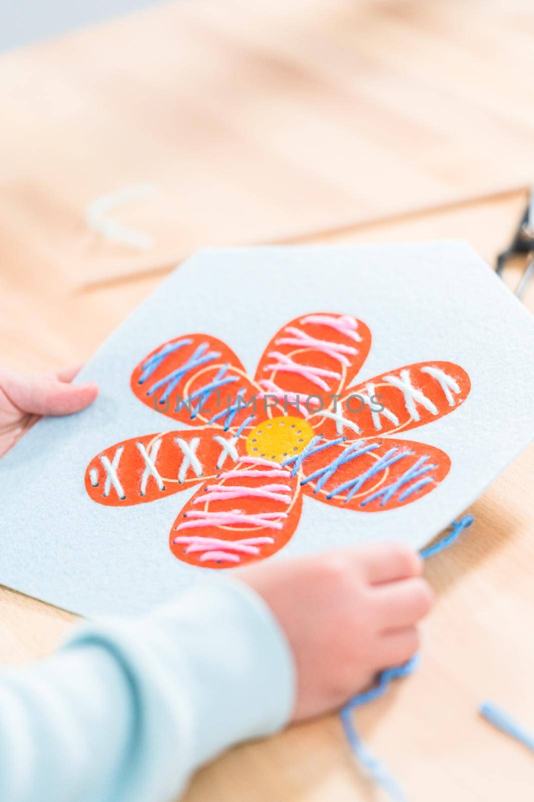 Little girl learning how to sew with sewing craft kit for kids.