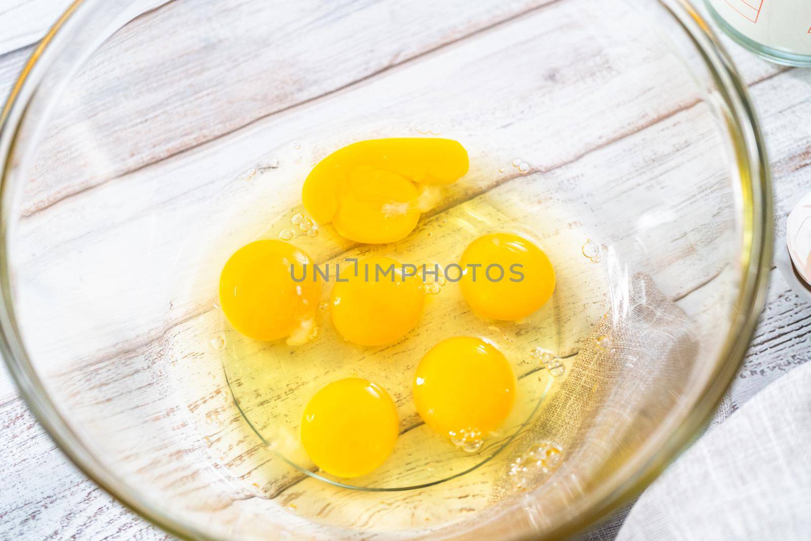 Ingredients in glass mixing bowls to prepare french toast on a wooden table.