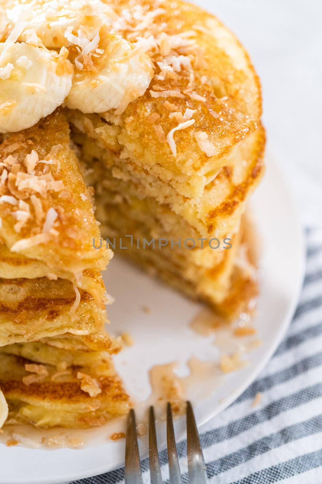 Eating freshly baked coconut banana pancakes garnished with sliced bananas and toasted coconut.