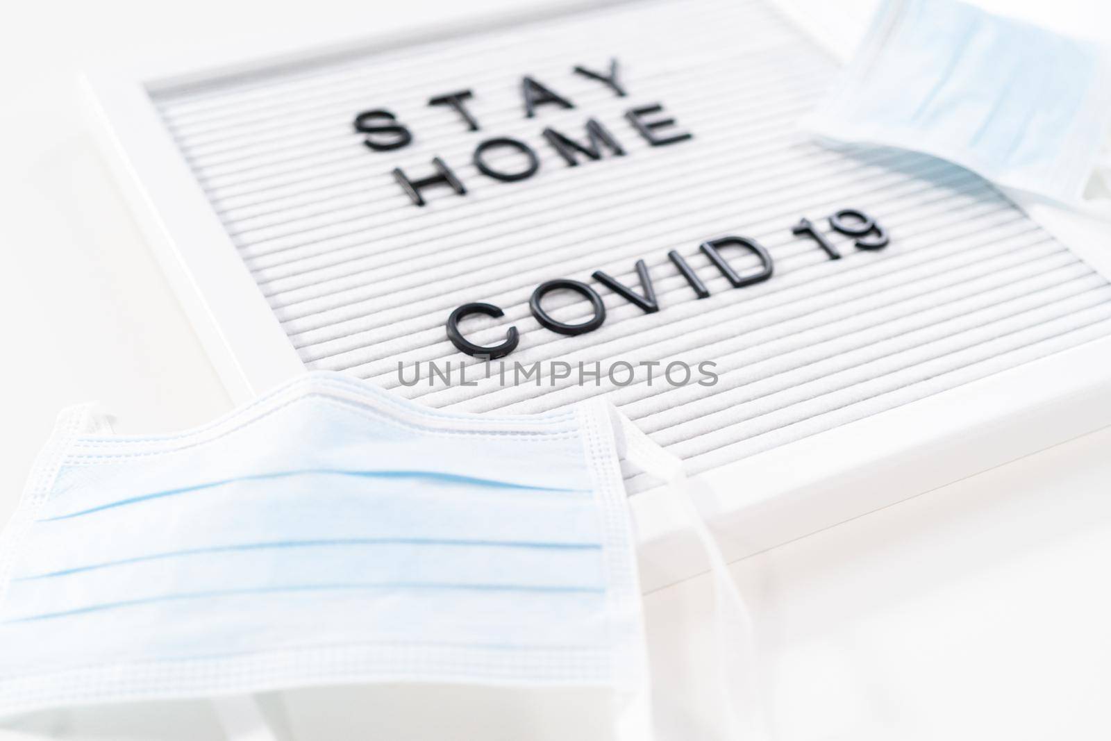 STAY HOME and COVID-19 sign on message board with a blue medical mask.