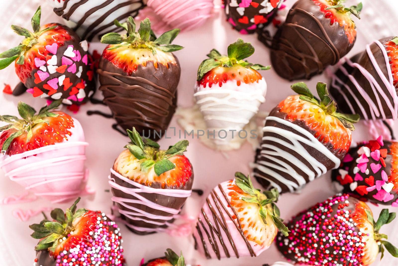 Variety of chocolate dipped strawberries on a pink cake stand.