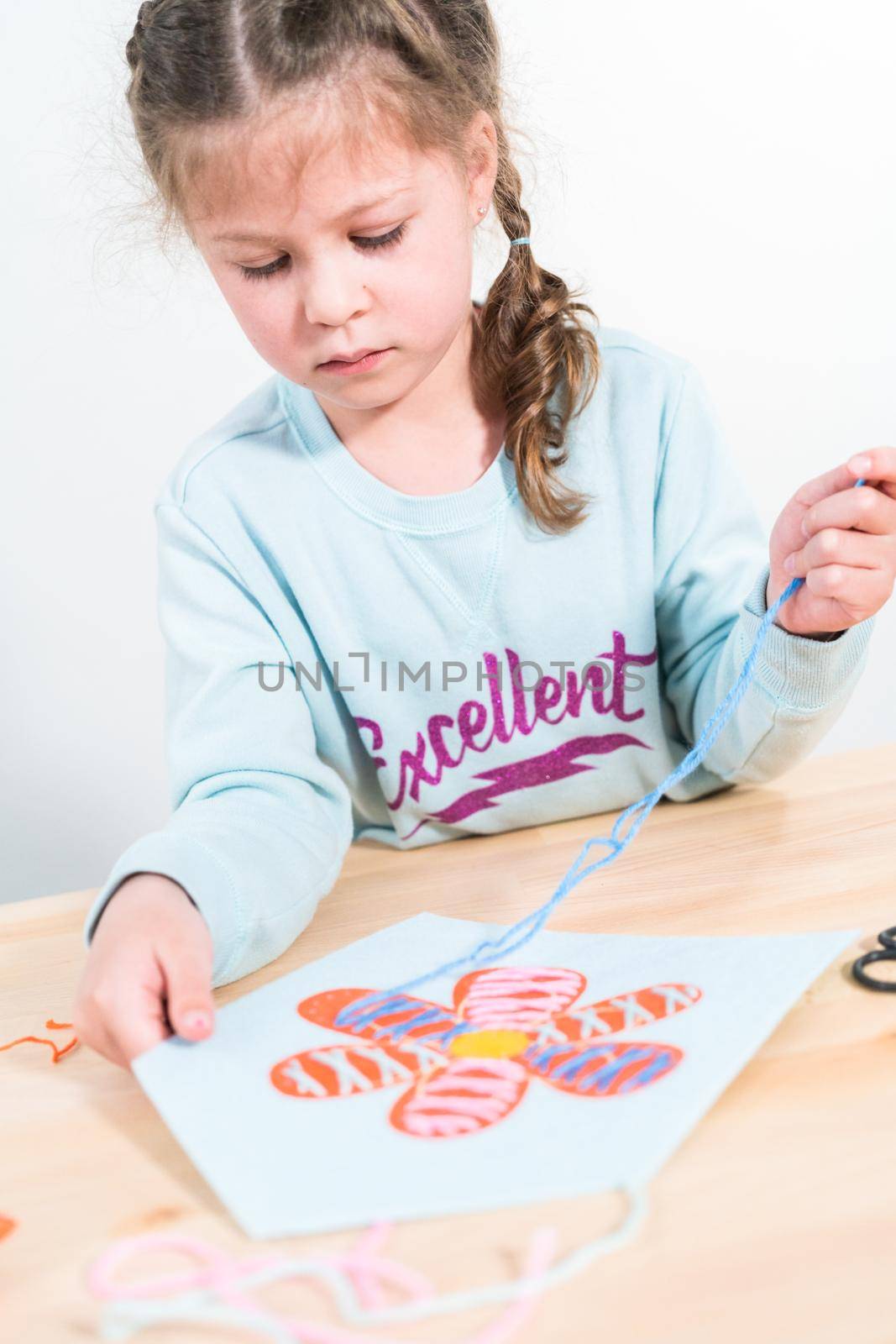 Little girl learning how to sew with sewing craft kit for kids.