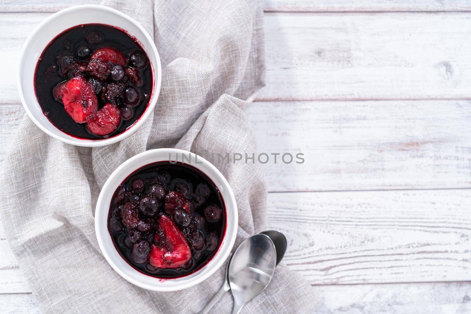 Homemade mix berry compote in small white bowls on a wooden table.