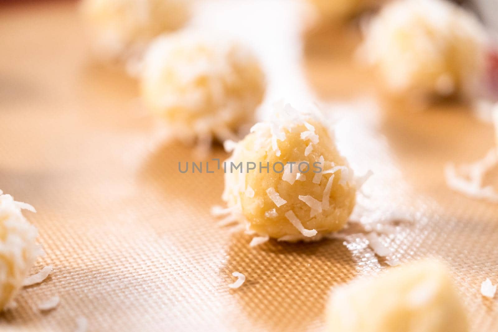 Unbaked dough scoops on the baking sheet to bake coconut cookies.