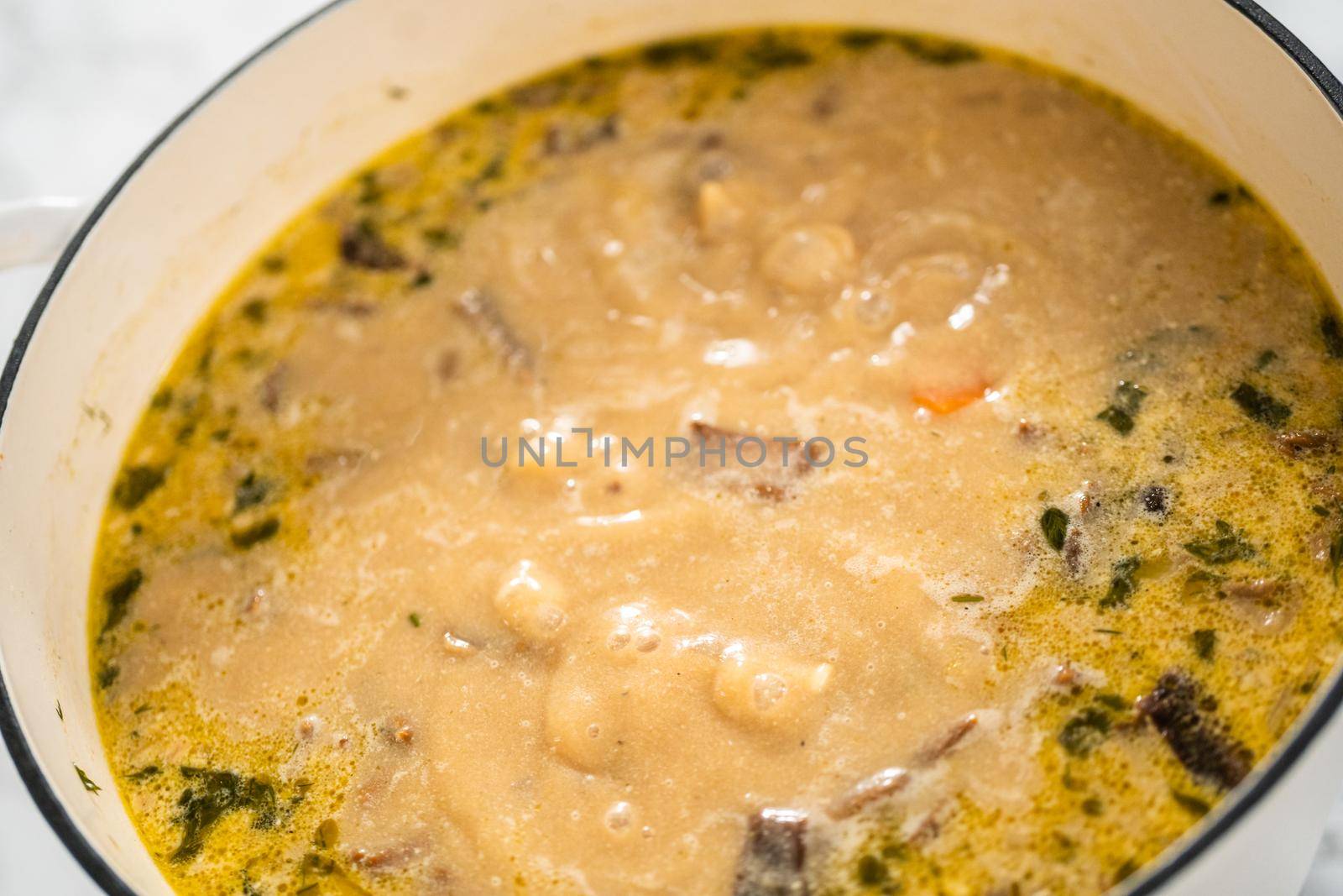 Cooking creamy wild mushroom soup made in an enameled dutch oven.