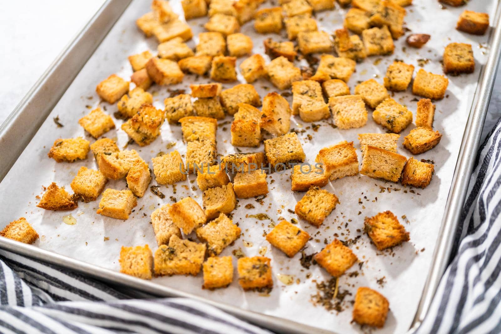 Cooling freshly dried croutons on a baking sheet lined with parchment paper.